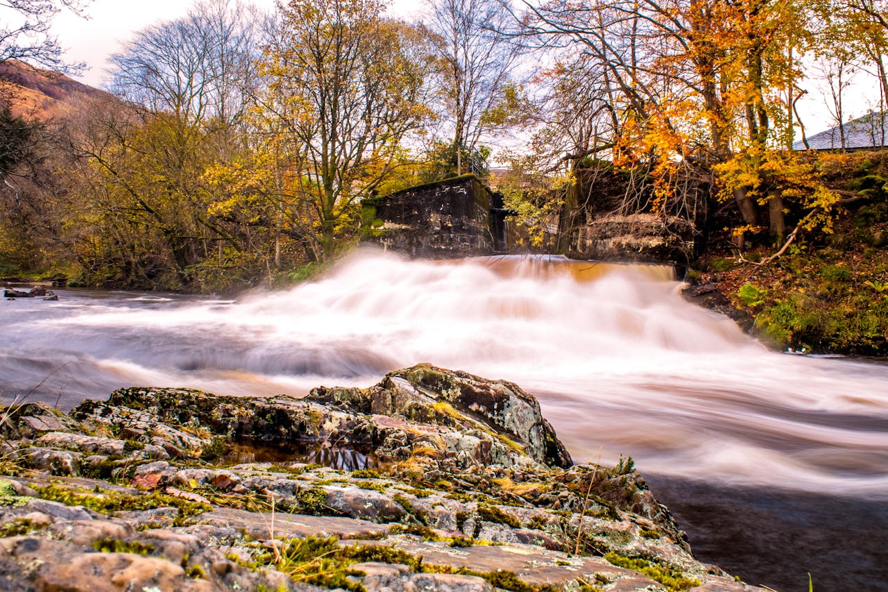 Serene waterfall flowing through a rocky landscape in Highland, Scotland during autumn.